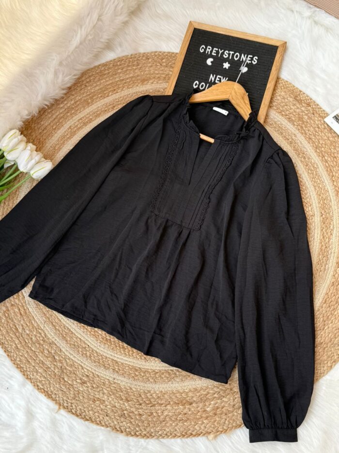 Black long sleeve blouse with ruffle neck and lace details laid flat