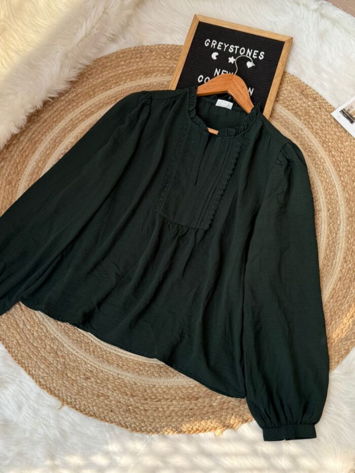 Bottle green long sleeve blouse with ruffle neck and lace details laid flat