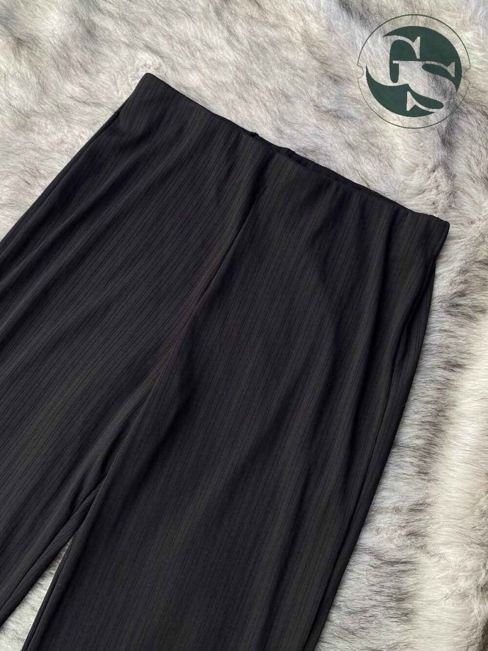 Elegant black wide-leg pleated pant displayed with lifestyle elements for a modern aesthetic.