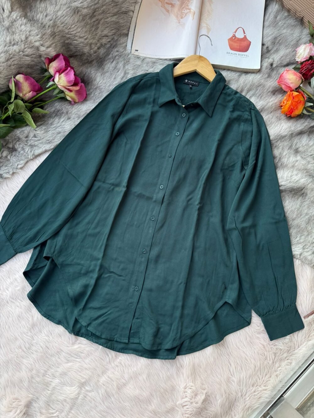 Solid forest green long sleeve button-down shirt for women, laid flat on faux fur background.