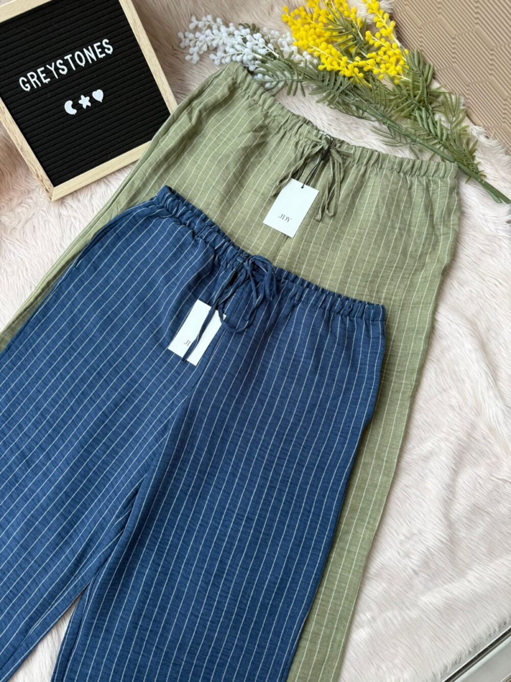 Flatlay of olive green and navy blue striped cotton wide-leg pants with drawstring waist
