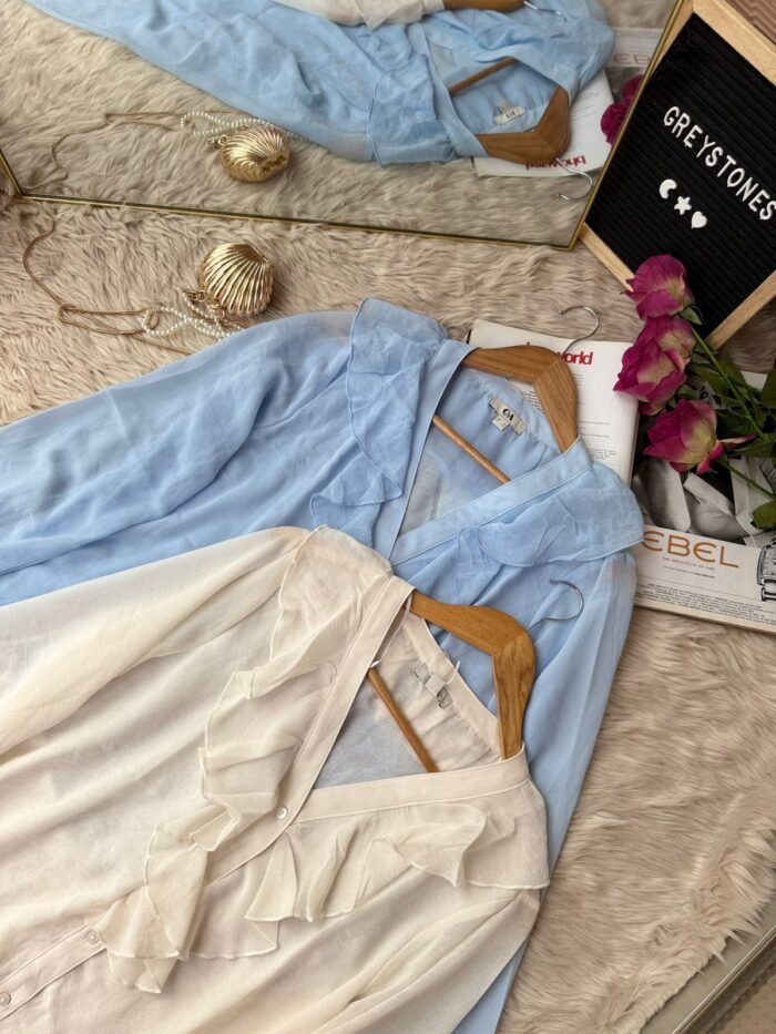 Elegant women’s ruffle V-neck chiffon tops in sky blue and ivory placed on wooden hangers – stylish button-down shirts for office and casual wear