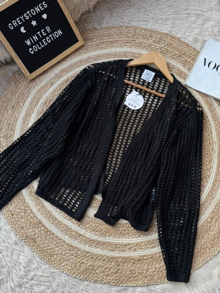 Black open-knit mesh cardigan on wooden hanger, part of winter collection