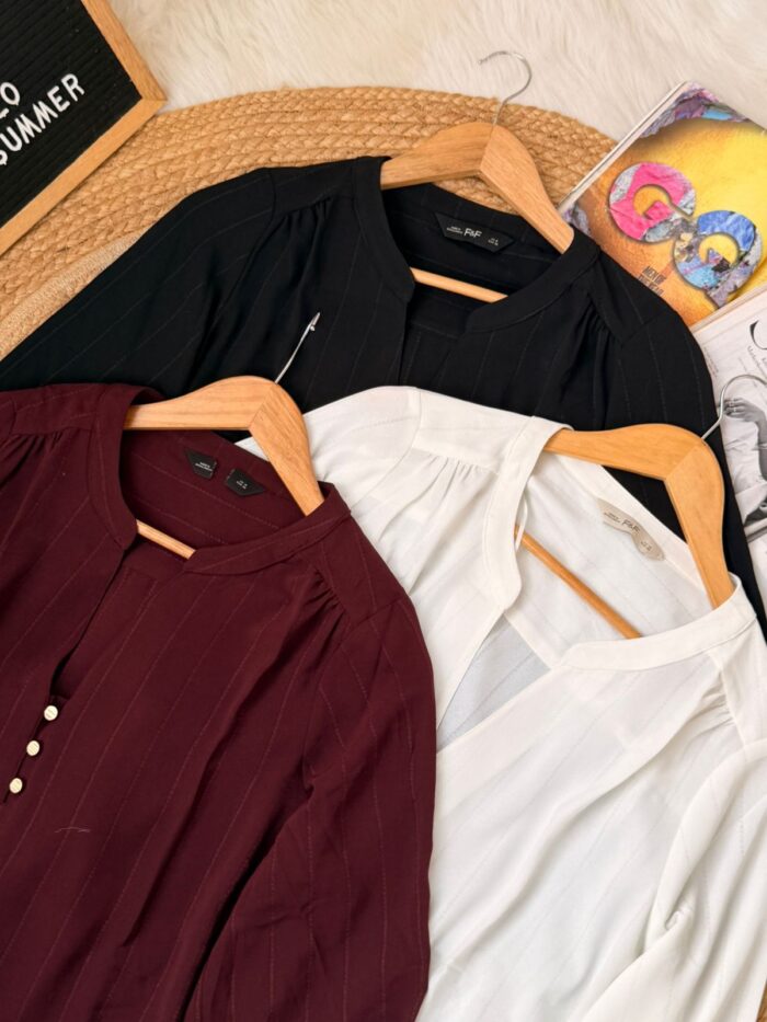 Women’s premium pinstripe blouse in maroon, black, and ivory white displayed on hangers, featuring mandarin collar and elegant casual design